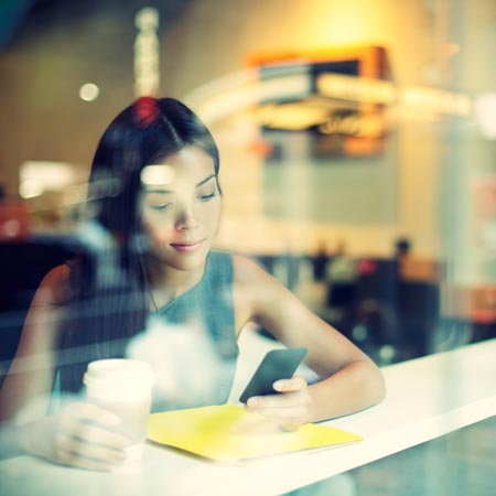 Mujer viendo su celular con un café