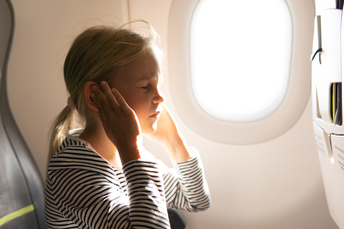 Niña con door en los oídos en el avión