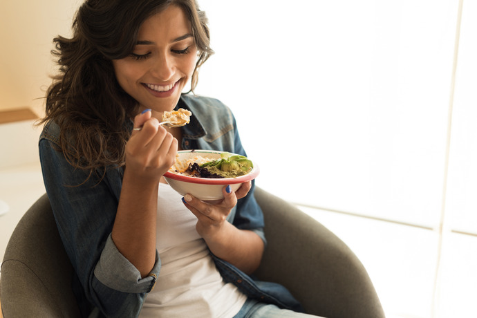 Mujer comiendo un plato de vegetales