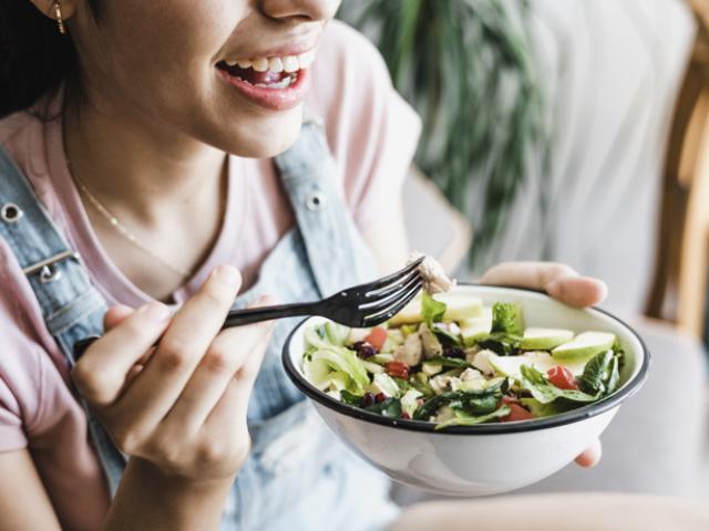 Mujer joven en República Dominicana disfrutando de una ensalada fresca como parte de su plan de alimentación saludable y déficit calórico.