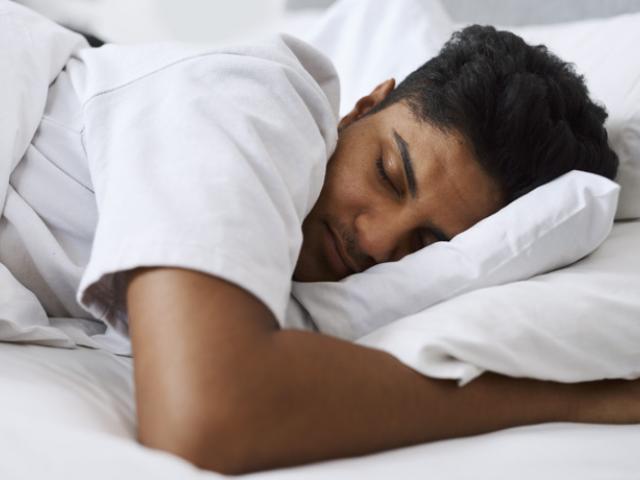 Joven dominicano duerme de forma relajada y profunda, ejemplificando cómo una rutina de descanso adecuada mejora la productividad en República Dominicana.