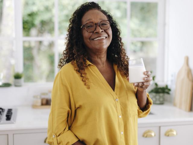 Mujer adulta mayor disfrutando un vaso de leche, fuente de calcio clave para prevenir la osteoporosis.