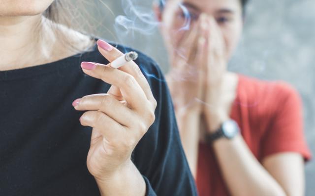 Ejemplo de fumadora pasiva evitando el humo del tabaco